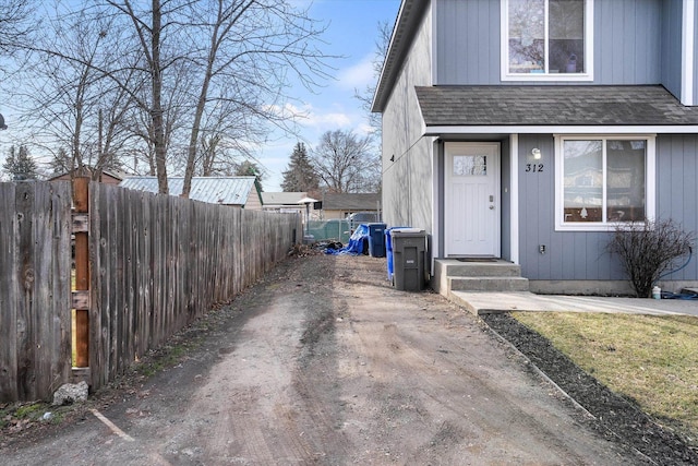 property entrance with fence and a shingled roof