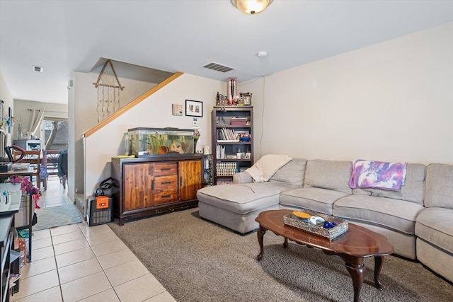 living room with visible vents, light tile patterned floors, and stairs