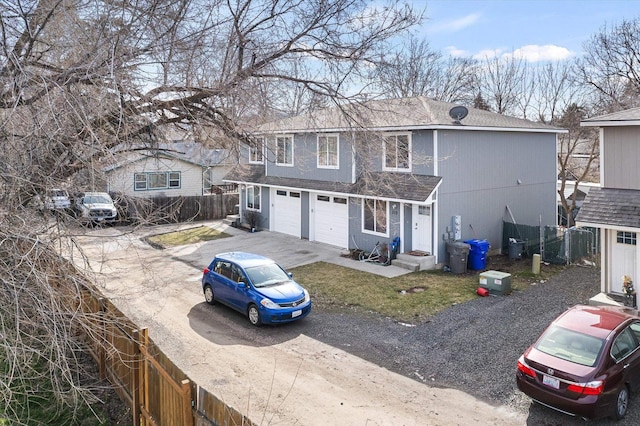 traditional-style home with concrete driveway, roof with shingles, fence, and an attached garage