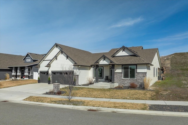 view of front of home featuring stone siding, a shingled roof, driveway, and a garage