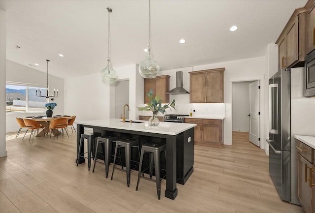 kitchen with light countertops, a sink, light wood-style floors, and wall chimney range hood
