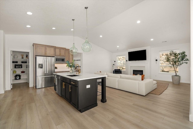 kitchen featuring a breakfast bar, light wood-style floors, stainless steel appliances, and a sink