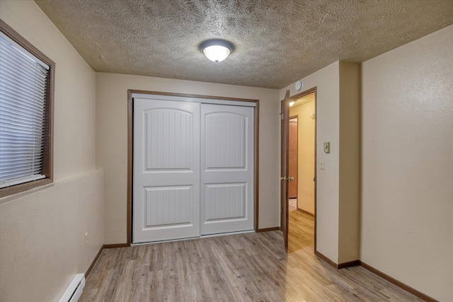 6208 N Wiscomb St, Spokane, WA 99208 - unfurnished bedroom with light wood-type flooring, a closet, a textured ceiling, and baseboard heating