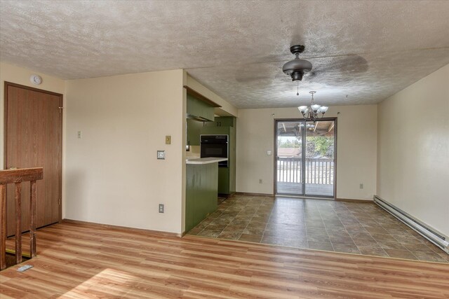 6208 N Wiscomb St, Spokane, WA 99208 - unfurnished room with a baseboard heating unit, a chandelier, a textured ceiling, wood finished floors, and a smoke detector