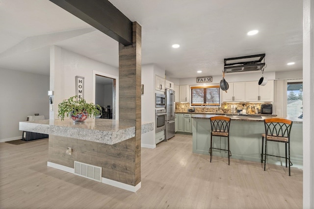 313 SE Trinity Ave, Wilbur, WA 99185 - kitchen featuring a breakfast bar area, light wood finished floors, a peninsula, recessed lighting, and stainless steel appliances