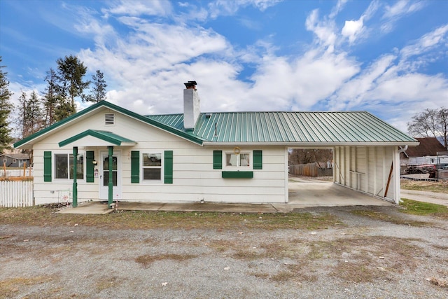 870 E 8th Ave, Colville, WA 99114 - view of front of house featuring a carport, a chimney, driveway, metal roof, and fence