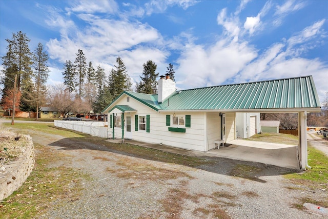 870 E 8th Ave, Colville, WA 99114 - rear view of property with a carport, metal roof, gravel driveway, and a chimney