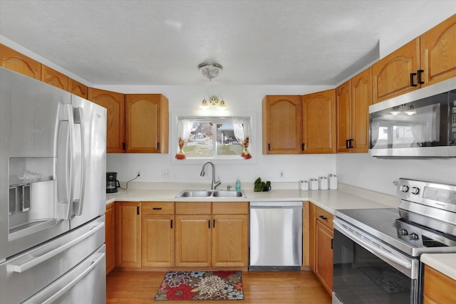 870 E 8th Ave, Colville, WA 99114 - kitchen with light countertops, light wood-type flooring, a sink, and appliances with stainless steel finishes