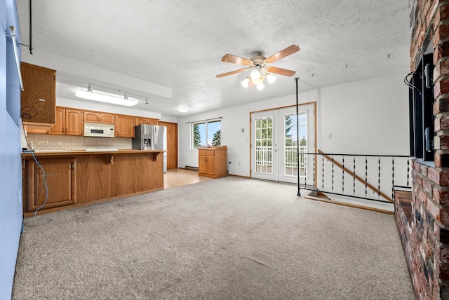 147 N Lindsey St, Tekoa, WA 99033 - kitchen with a textured ceiling, ceiling fan, stainless steel fridge with ice dispenser, white microwave, and light colored carpet