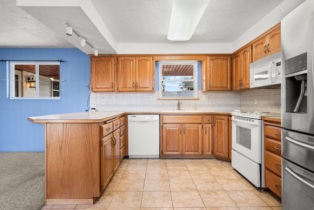 147 N Lindsey St, Tekoa, WA 99033 - kitchen featuring a peninsula, tasteful backsplash, brown cabinetry, and white appliances