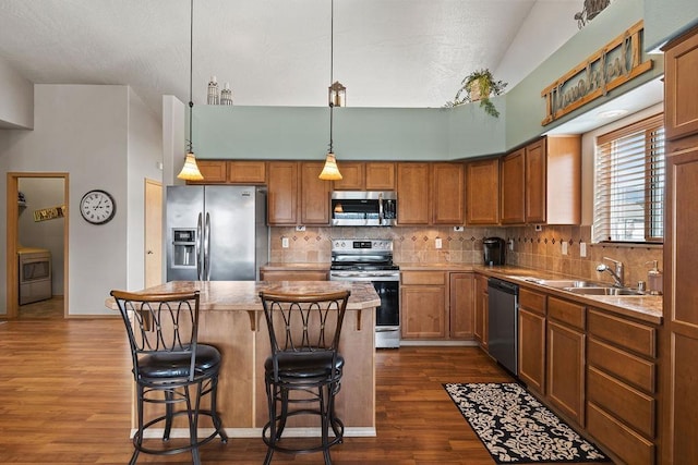 kitchen with backsplash, a kitchen island, appliances with stainless steel finishes, dark wood finished floors, and a sink