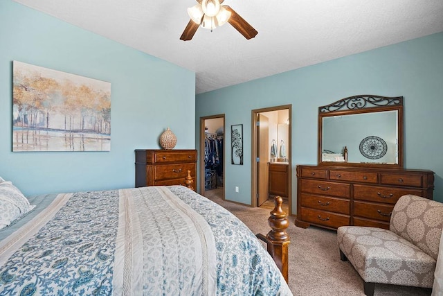 bedroom featuring a walk in closet, ceiling fan, a closet, connected bathroom, and carpet