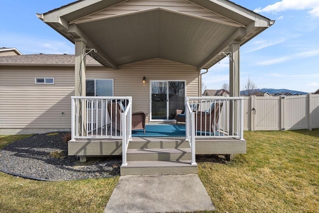 exterior space with a lawn, a gate, a wooden deck, and fence