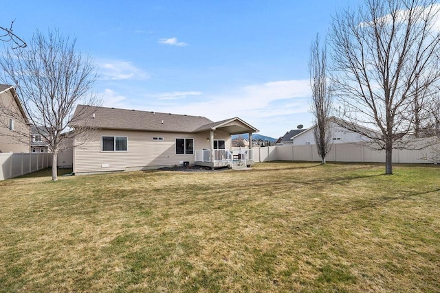 rear view of house with a fenced backyard, a lawn, and a deck
