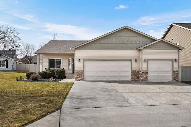 view of front of property featuring driveway, a front yard, fence, an attached garage, and stone siding