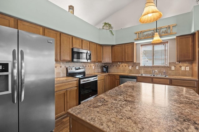 kitchen with brown cabinetry, lofted ceiling, tasteful backsplash, a sink, and appliances with stainless steel finishes