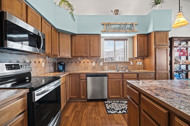 kitchen with brown cabinetry, a sink, dark wood finished floors, and appliances with stainless steel finishes