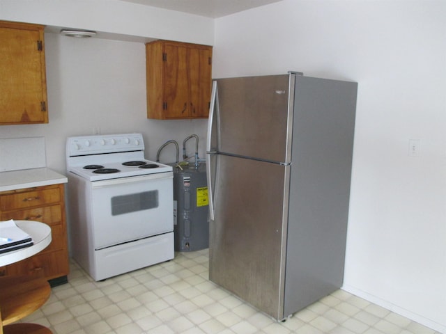 1914 W 8th Ave, Spokane, WA 99204 - kitchen with light countertops, white range with electric cooktop, freestanding refrigerator, brown cabinets, and light floors