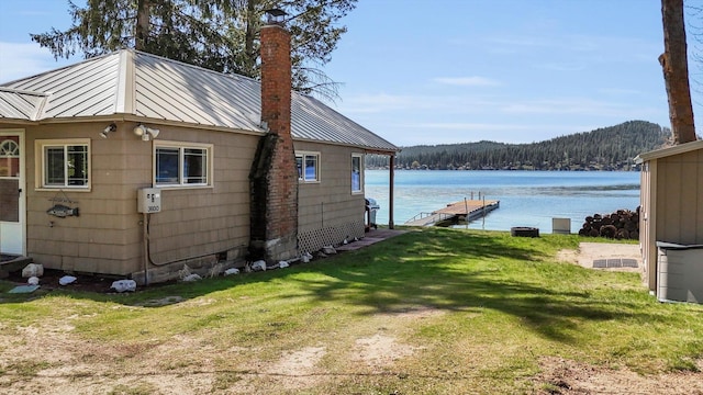 exterior space featuring a water view, a dock, and a wooded view