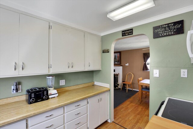 kitchen with electric stove, white cabinets, arched walkways, and light countertops