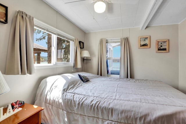bedroom with beamed ceiling, multiple windows, and ceiling fan