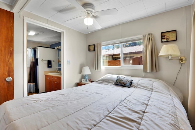bedroom featuring a ceiling fan, ensuite bath, and a sink