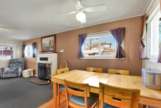 carpeted dining area with a fireplace and ceiling fan