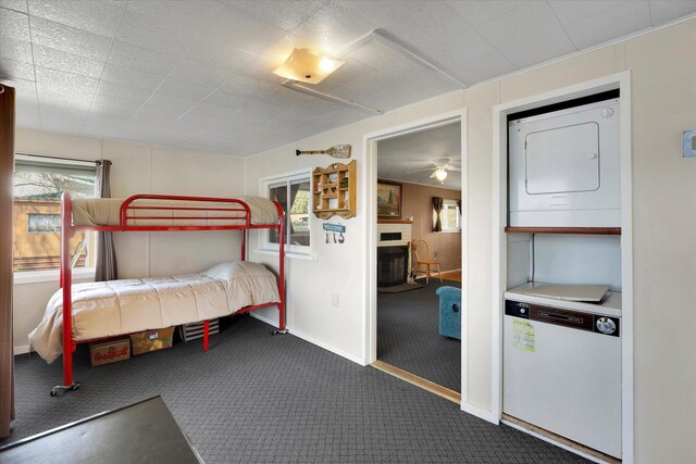 bedroom with a fireplace, stacked washer / drying machine, carpet flooring, and baseboards