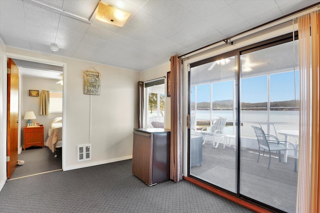 spare room featuring baseboards, a water view, and carpet flooring