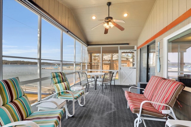sunroom with a ceiling fan and a water view