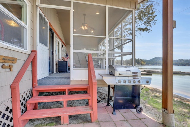 exterior space featuring area for grilling, a water view, and a sunroom