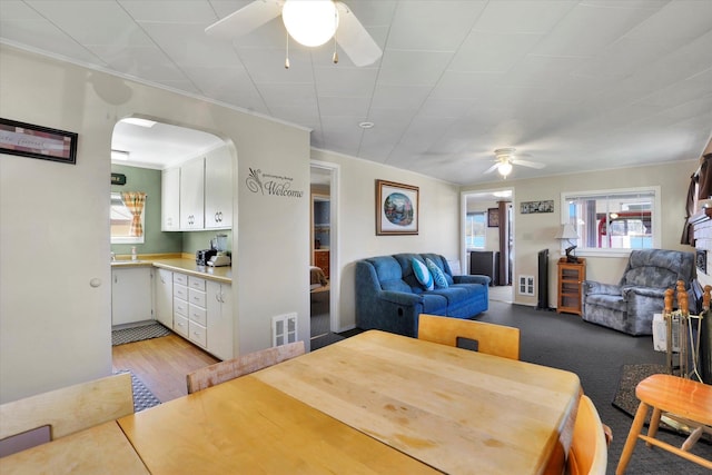 dining area with wood finished floors, a ceiling fan, ornamental molding, and arched walkways