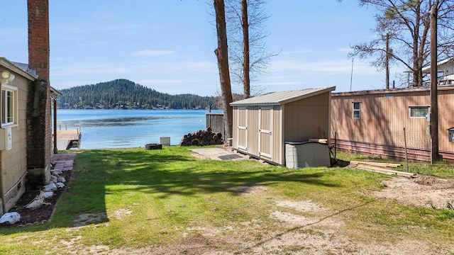 view of yard with a storage shed, a water view, and an outdoor structure