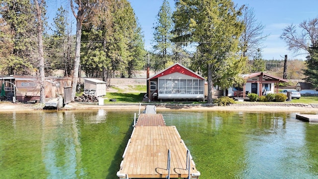 view of dock with a yard, a water view, and a fire pit