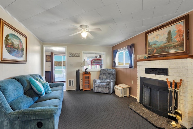 carpeted living room with a brick fireplace, ceiling fan, and baseboards