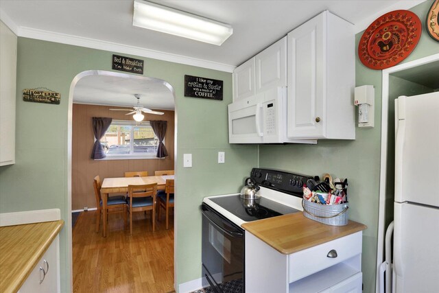 kitchen featuring white cabinetry, light countertops, arched walkways, light wood finished floors, and white appliances