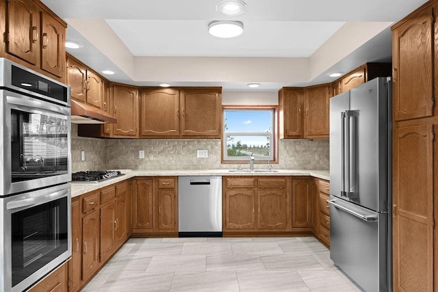 12115 E Wedgewood Ct, Spokane, WA 99217 - kitchen featuring stainless steel appliances, brown cabinets, light countertops, under cabinet range hood, and recessed lighting