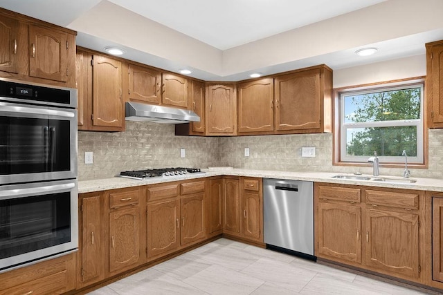 12115 E Wedgewood Ct, Spokane, WA 99217 - kitchen with appliances with stainless steel finishes, under cabinet range hood, a sink, brown cabinets, and backsplash