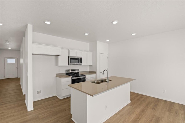 kitchen with white cabinets, light wood finished floors, appliances with stainless steel finishes, an island with sink, and a sink