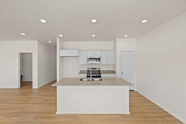 kitchen with white cabinets, light wood-style flooring, stainless steel appliances, and light countertops