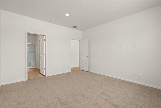unfurnished bedroom with light carpet, a textured ceiling, baseboards, and visible vents