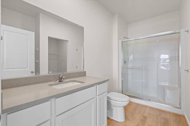 full bathroom with wood finished floors, a stall shower, toilet, and vanity