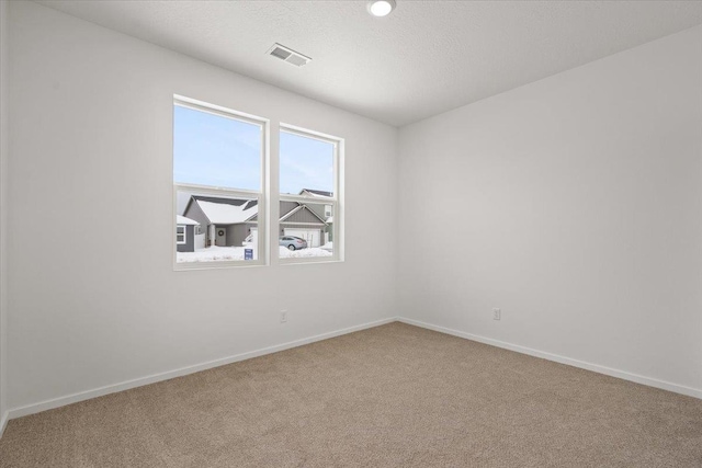 empty room with baseboards, carpet flooring, a textured ceiling, and visible vents