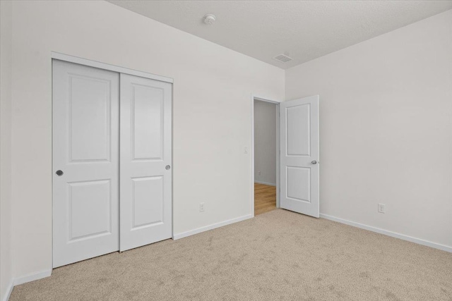 unfurnished bedroom featuring carpet floors, a closet, baseboards, and visible vents