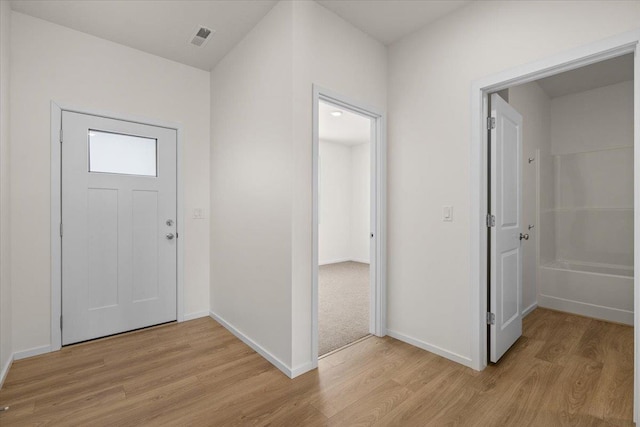 entryway with baseboards, visible vents, and light wood finished floors