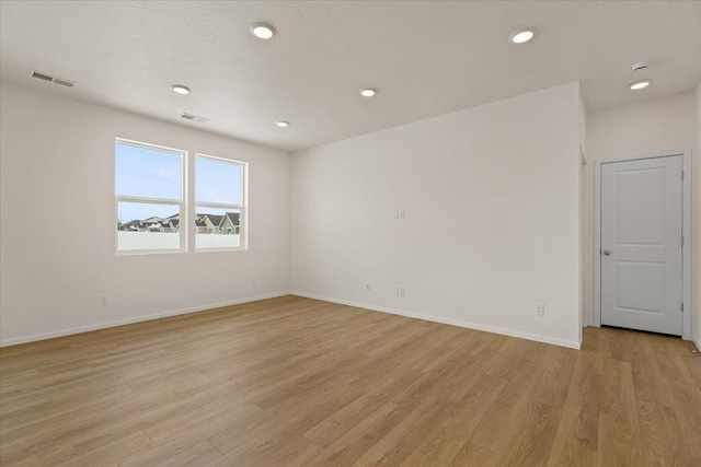 empty room with baseboards, light wood-style flooring, visible vents, and recessed lighting