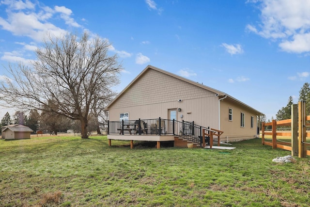 rear view of house with an outdoor structure, fence, a deck, and a yard