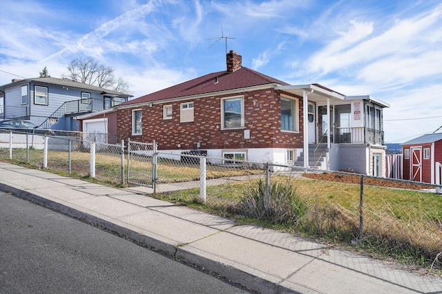 view of side of property with a gate, a chimney, an outbuilding, brick siding, and a fenced front yard