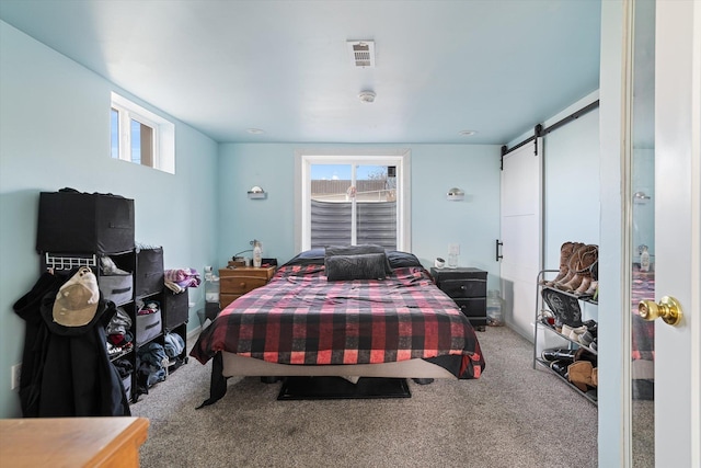 carpeted bedroom featuring a barn door and visible vents