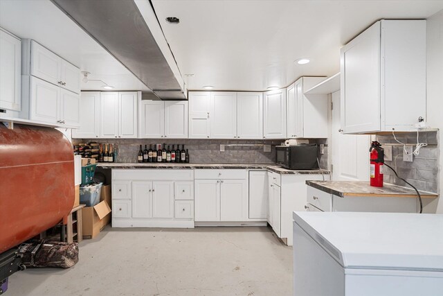 kitchen featuring black microwave, white cabinets, and tasteful backsplash